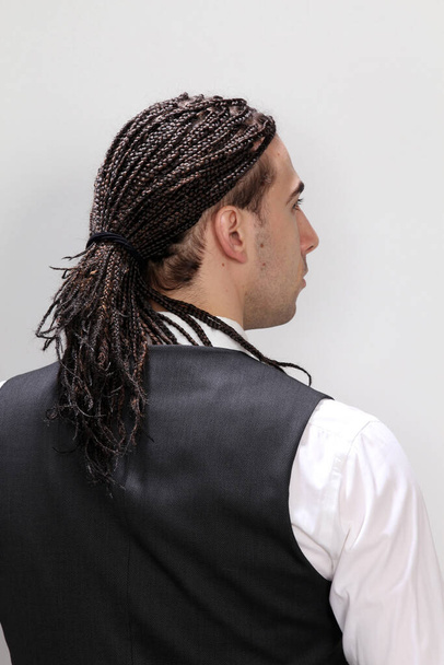 Stylish male model with afro braids posing in studio on isolated background. Style, trends, fashion concept. - Photo, image