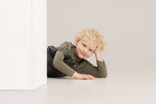 Πορτρέτο του μικρού παιδιού προσχολικής ηλικίας θέτει απομονωμένη πάνω από γκρι φόντο στούντιο. - Φωτογραφία, εικόνα