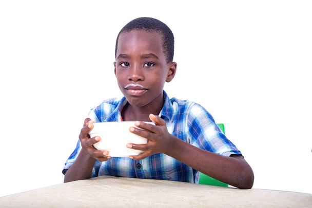 красивый маленький мальчик сидит за столом и пьет йогурт дома. - Фото, изображение