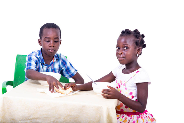 милі маленькі діти снідають, тримаючи хліб за столом вдома
. - Фото, зображення