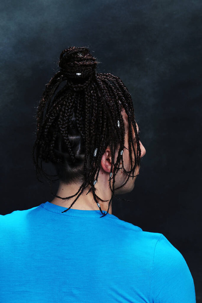 Stylisches männliches Model mit Afro-Zöpfen posiert im Studio auf isoliertem Hintergrund. Stil, Trends, Modekonzept. - Foto, Bild