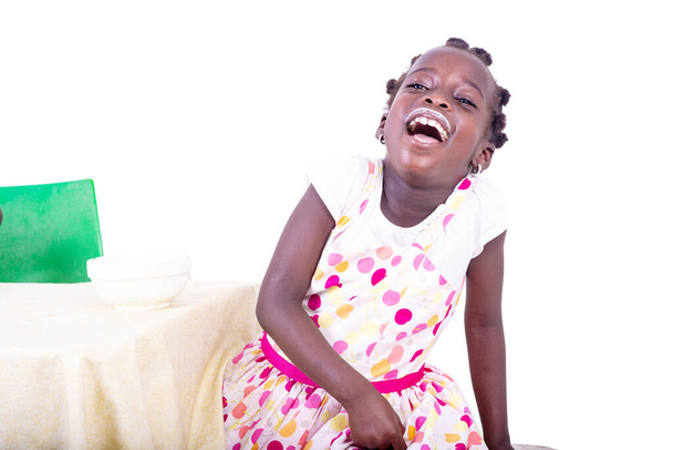 schönes kleines Mädchen lacht, während es einen Joghurt-Schnurrbart trägt. - Foto, Bild