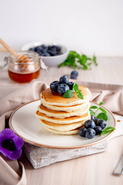 Homemade pancakes with blueberries and powdered sugar on the white table vertical photo - Foto, Imagen