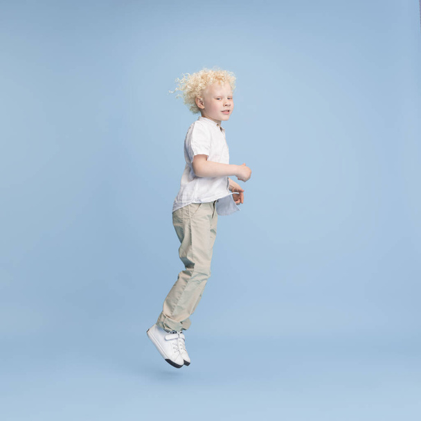 Mavi stüdyo arka planında izole edilmiş mutlu çocuk portresi. - Fotoğraf, Görsel