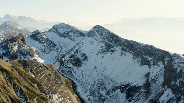 Vista aérea de tirar o fôlego de uma manhã gelada no vale montanhoso. HDR. Belos picos de montanha pontiagudos em uma névoa matinal e sol . - Foto, Imagem
