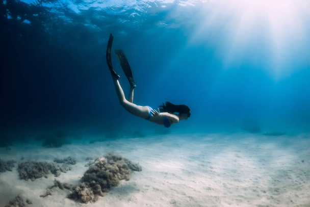 Ελκυστική ελεύθερη δύτης γυναίκα με πτερύγια βουτιά σε βαθιά υποβρύχια στη θάλασσα. - Φωτογραφία, εικόνα