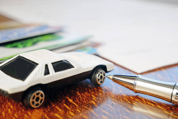 Banka kartları ve beyaz araba oyuncakları masada, araba sigortası konsepti, yakın plan. - Fotoğraf, Görsel