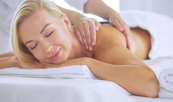 Young woman enjoying massage in spa salon - Foto, immagini