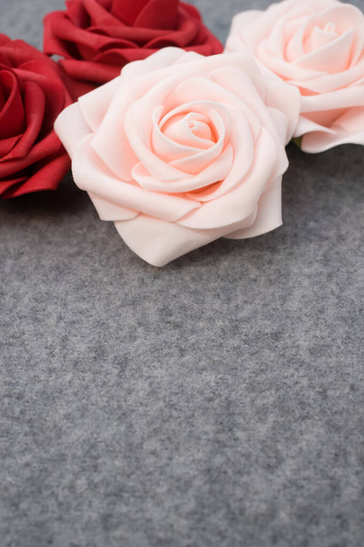 A vertical shot of pink and red roses on a woolen background with copy space below - Foto, Imagem