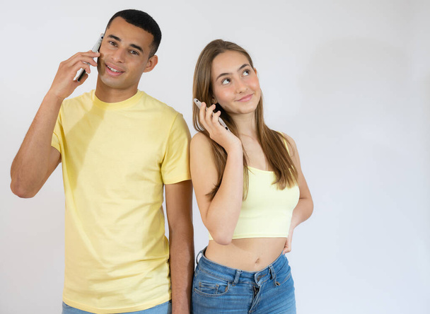 Cheerful young couple talking on mobile phones isolated over white background - Φωτογραφία, εικόνα