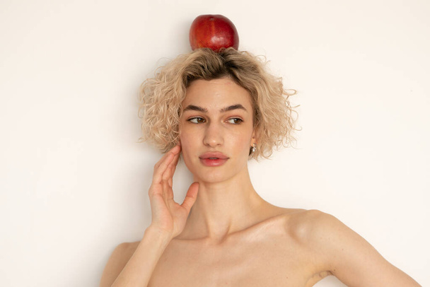 portrait of a young beautiful woman with an apple on my head - Fotoğraf, Görsel