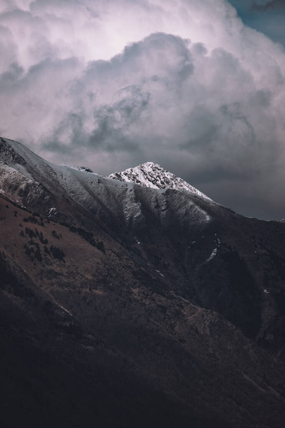 A vertical shot of snow-covered mountains under a cloudy sky - Foto, immagini
