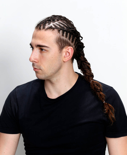 Attractive guy with braids posing in studio on isolated background. Style, trends, fashion concept. - Photo, Image