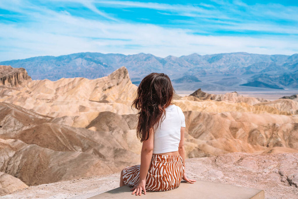 A beautiful young woman in a skirt stands in the middle of a desert landscape in Death Valley Zabriskie Point, USA. - Photo, image