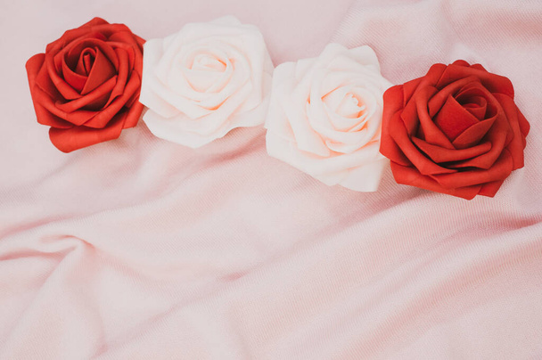 A line of pink and red roses on a wrinkled fabric background with copy space - Φωτογραφία, εικόνα