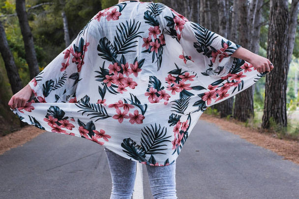 A female with flowery jacket walking on the road - 写真・画像