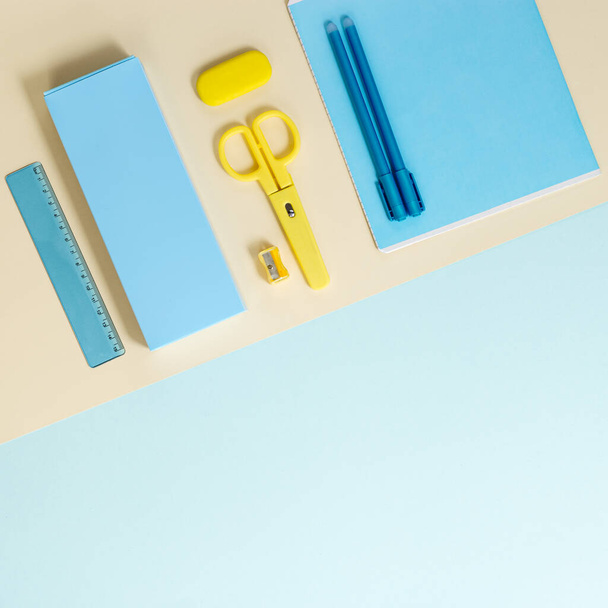 Flat lay of stationery and school supplies, notebooks, pencil case, pens, pencils, scissors, erasers on colored background, blue and yellow pastel colored. Back to school concept. Top view. - Foto, Imagem