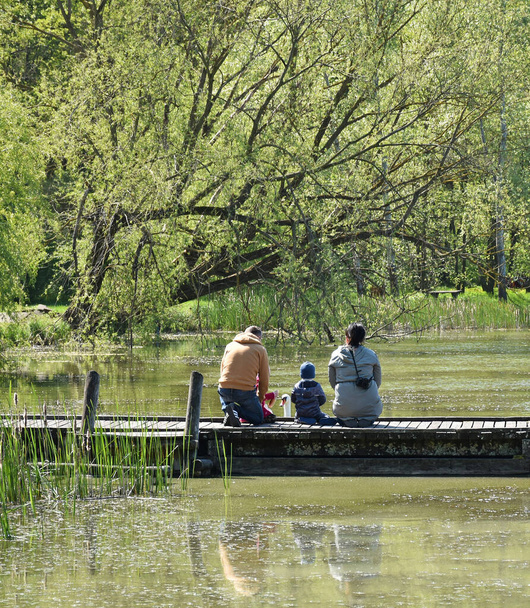 Family on the pier of the lake in spring time - Foto, imagen