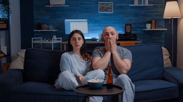 Sorprendida joven pareja asombrada mirando el programa documental en la televisión - Foto, imagen