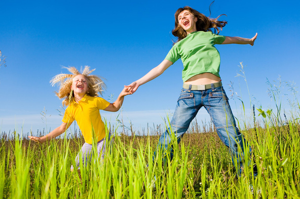 Happy woman and girl making exercises on field. - Фото, зображення