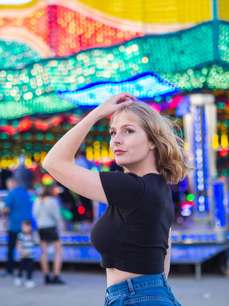 A vertical shot of a young blonde female at an amusement park - Fotoğraf, Görsel