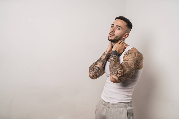 A portrait of a cool sexy tattooed Spanish male posing isolated on a white background - Фото, изображение