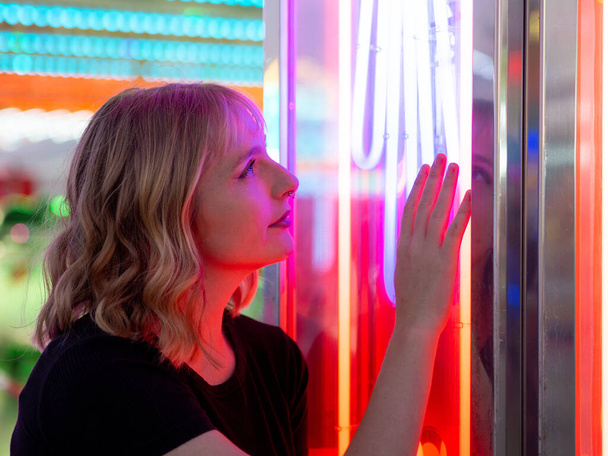 A young blonde female looking at laser lights at an amusement park - Fotoğraf, Görsel