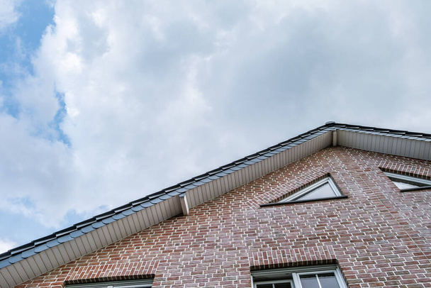 A low angle of an old brick-walled house under a cloudy sky - Zdjęcie, obraz