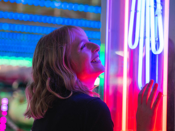 A young blonde female looking at laser lights at an amusement park - Foto, Imagem