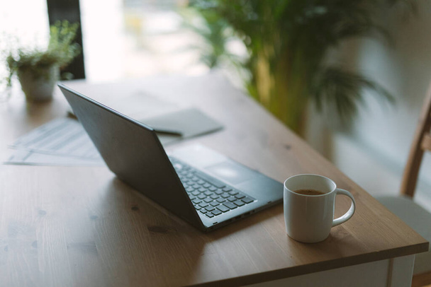 A closeup shot of an open laptop and a cup of coffee on an office desk - Fotoğraf, Görsel