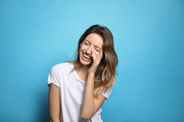 Cheerful young woman laughing on light blue background - Фото, зображення