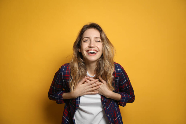 Cheerful young woman laughing on yellow background - Φωτογραφία, εικόνα
