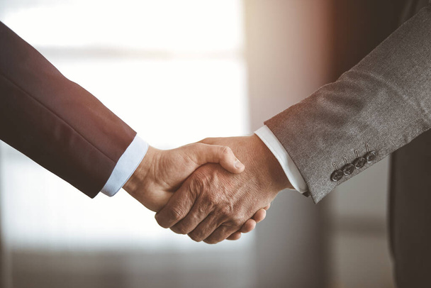 Business people standing and shaking hands in sunny office, close-up. Handshake and marketing - Photo, Image