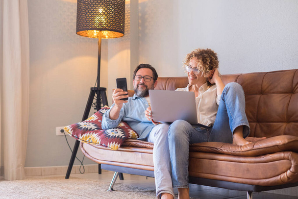 Mensen thuis met computer en smartphone genieten van tijd samen - Foto, afbeelding
