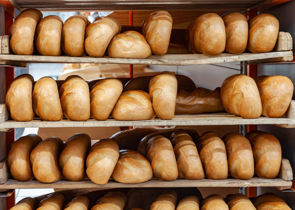 Lots fresh crisp loaves of bread. Shelves full with fresh golden bread. Freshly baked bread lies on the shelf for sale - Fotoğraf, Görsel