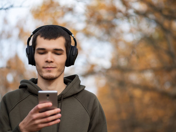 Portrait of a man in the autumn Park with headphones . Lifestyle. Autumn walks - Фото, изображение