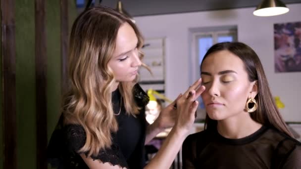 makeup umělec dělá make-up pro atraktivní mladé asijské ženy v salonu krásy - Záběry, video