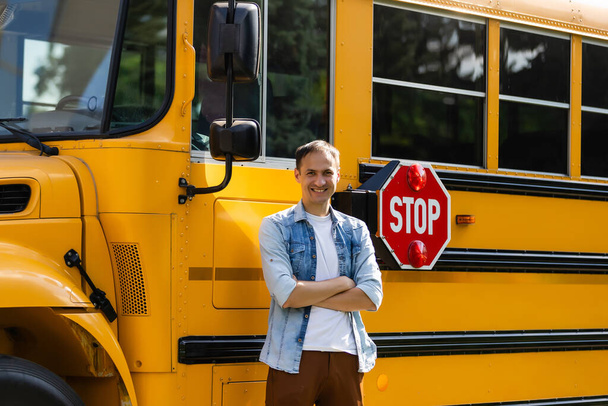 Uśmiechnięty kierowca autobusu patrzący w kamerę przed szkołą podstawową - Zdjęcie, obraz