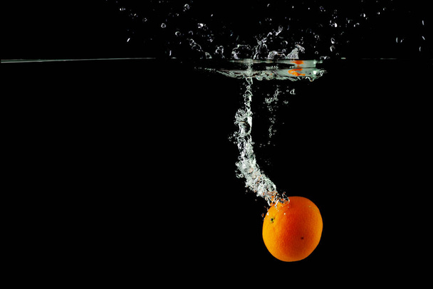 tangerine in water on a black background, place under the text - 写真・画像