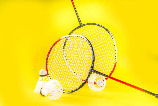 Concept d'activité sportive d'été. Deux raquettes de badminton avec des navettes sur fond jaune vif tendance  - Photo, image