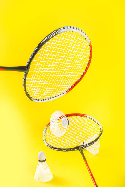 Yaz sporları konsepti. İki badminton raketi ve parlak sarı arka planda mekik horozu.  - Fotoğraf, Görsel