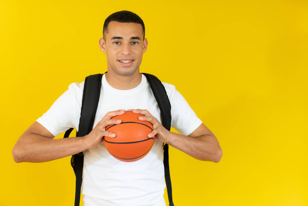 happy handsome student holding a basketball isolated over white background. - Fotó, kép