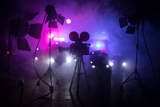 Koncepcja filmu akcji. Radiowozy i miniaturowy film na ciemnym tle z mgłą. Radiowóz ściga samochód w nocy. Miejsce wypadku zbrodniczego. Skupienie selektywne - Zdjęcie, obraz