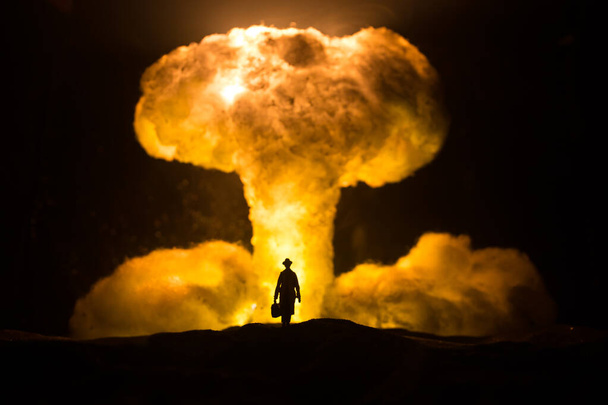 Nükleer savaş konsepti. Nükleer bomba patlaması. Karanlıkta yaratıcı sanat dekorasyonu. Bir insanın siluetine karşı dev mantar bulutu atomik patlama. Seçici odak - Fotoğraf, Görsel