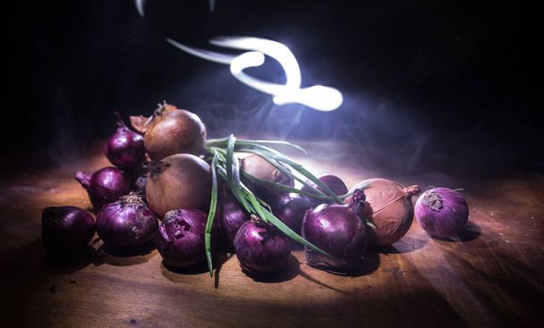 Vegetable concept. Different onions on wood in dark. Selective focus. Colorful background. - Fotografie, Obrázek