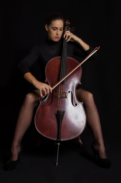 Beautiful woman playnig a cello with selective light and black d - Photo, Image