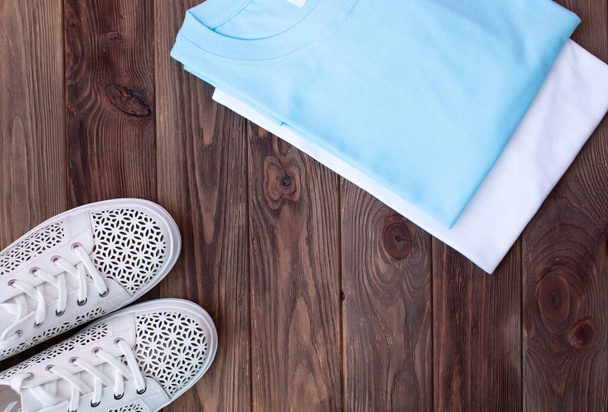 top view of stylish white sneakers and clothes on brown wooden background    - Photo, image