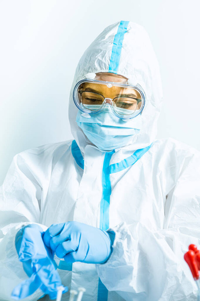 Female doctor or nurse during coronavirus pandemic covid-19. Frontline health care worker in ppe, glasses and mask put on antiviral suit or costume. Health care practitioner in the vaccine laboratory - Foto, Imagen