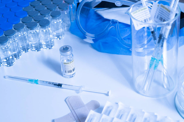 Glass bottle vial and syringe with Covid-19 Coronavirus vaccine in a research medical facility lab. Ampoules with cure on the medical worker laboratory table. Sars-cov-2 pandemic concept.  - Zdjęcie, obraz