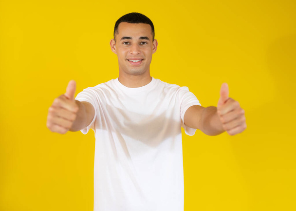 Mladý muž s palci nahoru přes žluté pozadí - Fotografie, Obrázek